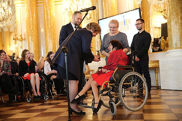 Siedząca na wózku Joanna Pąk odbiera statuetkę z rąk Teresy Hernik, prezes PFRON