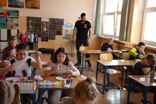 asystent patrzący na pracę dziecka w klasie podczas rysowania