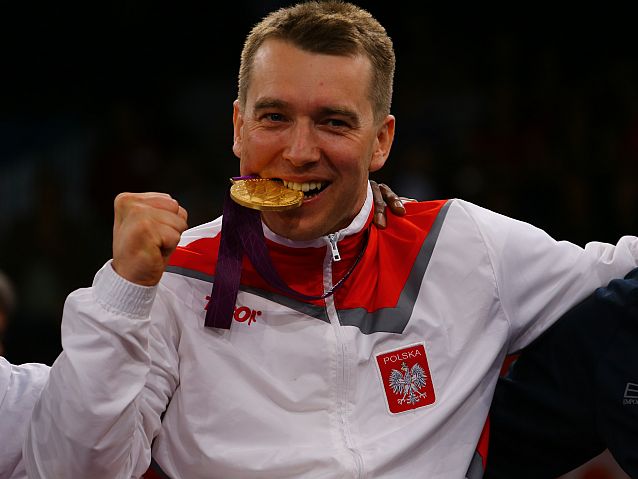 Polski zawodnik trzyma w zębach swój złoty medal