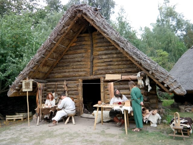 przed chatą siedzi kilka osób przebranych za pradawnych słowian