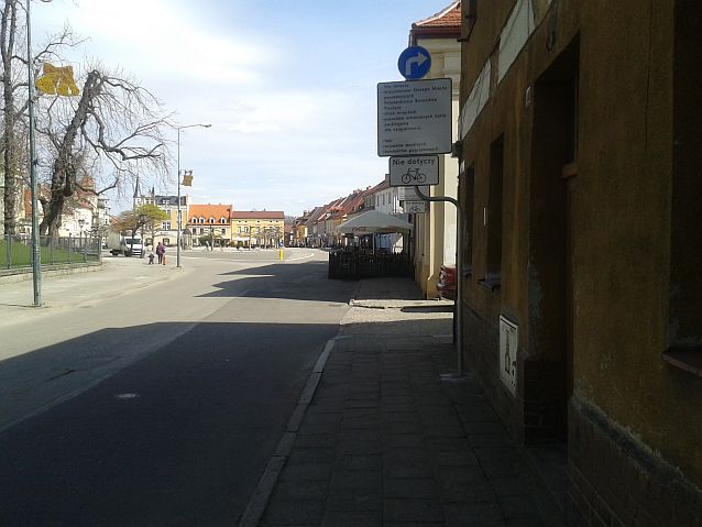 Widok na rynek w Pszczynie i znak, który nakazuje skręcić przed rynkiem w prawo