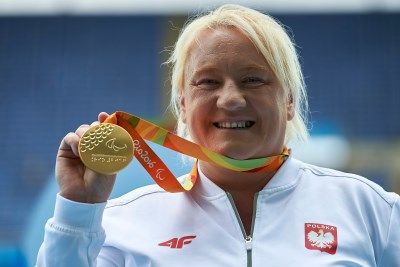 Uśmiechnięta Ewa Durska trzyma w ręku swój złoty medal Igrzysk Paraolimpijskich w Rio