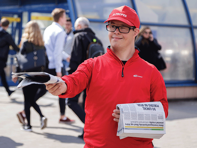 mężczyzna z zespołem Downa rozdaje gazety przy metrze