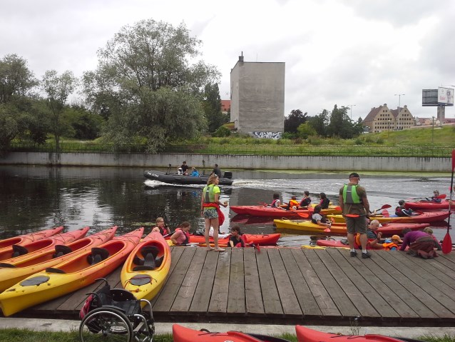 wolontariusze patrzą z pomostu na uczestników projektu w kajakach