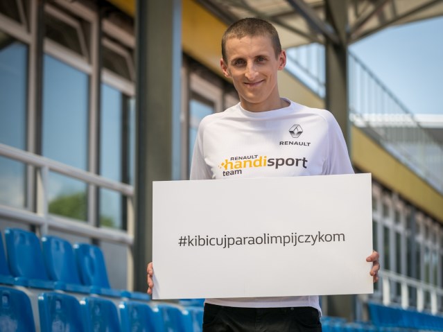 Maciej Lepiato trzyma tabliczkę z napisem #kibicujparaolimpijczykom