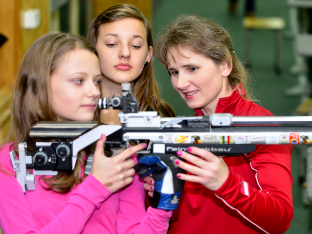 Renata Mauer-Różańska pokazuje dwóm dziewczynom jak strzelać