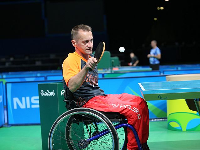 Maciej Nalepka na wózku odbija piłeczkę przy stole do tenisa