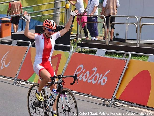 Anna Harkowska na mecie wyścigu rowerowego unosi ręce w geście triumfu