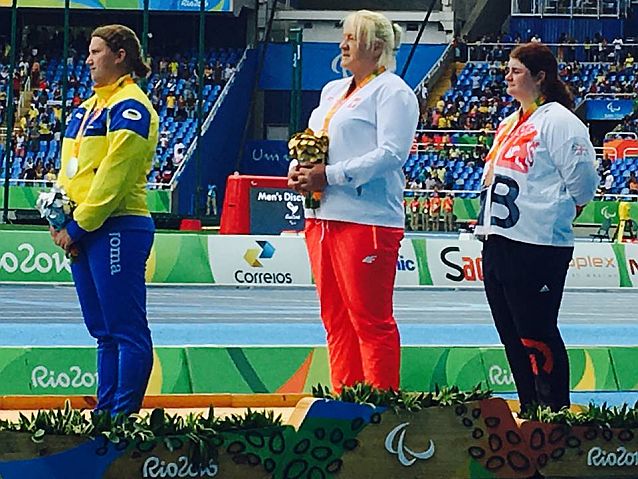 Ewa Durska z medalem na szyi stoi na najwyższym stopniu podium, obok niej Ukrainka i Brytyjka