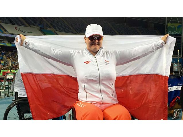 Uśmiechnięta Lucyna Kornobys trzyma polską flagę