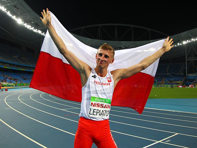 Maciej Lepiato na bieżni z rozpostartą nad głową flagą Polski