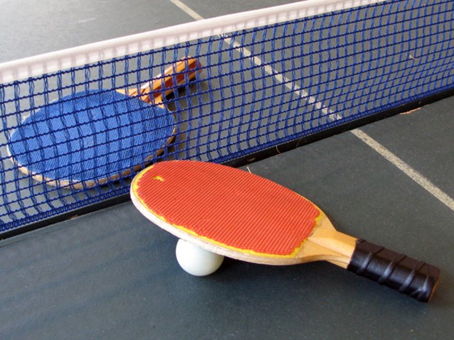 dwie rakietki leżą na stole tenisowym przy piłeczce