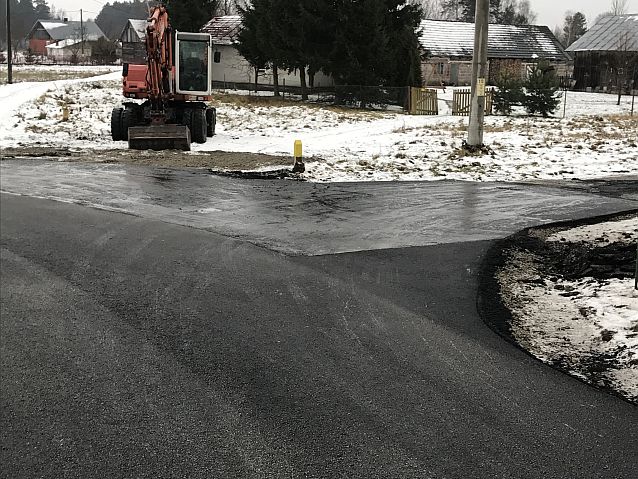 Zakręt i rozwidlenie asfaltowej drogi, w tle koparka