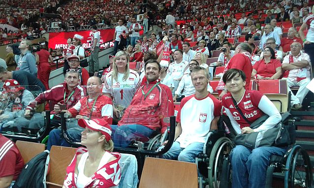 Ubrani w stroje reprezentacji Polsi kibice na wózkach siedzą w tłumie kibiców na trybunach