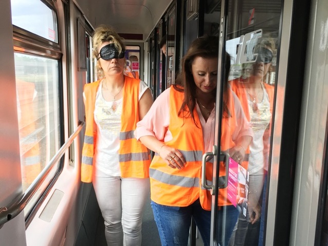 szkolenie w pkp intercity: kobieta prowadzi do przedziału kobietę, która ma opaskę na oczach