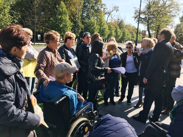 protestujący rodzice i opiekunowie stoją w kręgu i rozmawiają podczas protestu