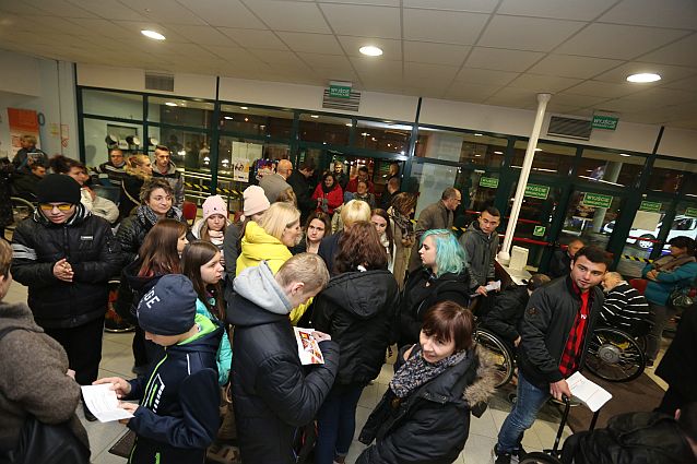 Tłum ludzi, w tym osoby na wózkach, przy wejściu do hali