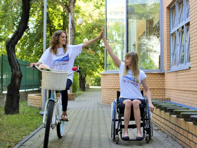 dziewczyna na rowerze i dziewczyna na wózku przybijają sobie piątki