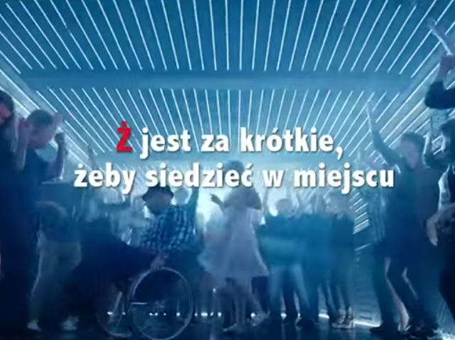 tańczący na wózku mężczyzna z napisem Ż jest za krótkie, żeby siedzieć w miejscu