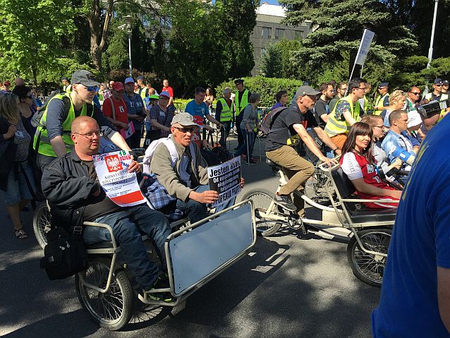 Manifestacja. Wśród idących protestujących są też osoby z transparentami jadące rikszami