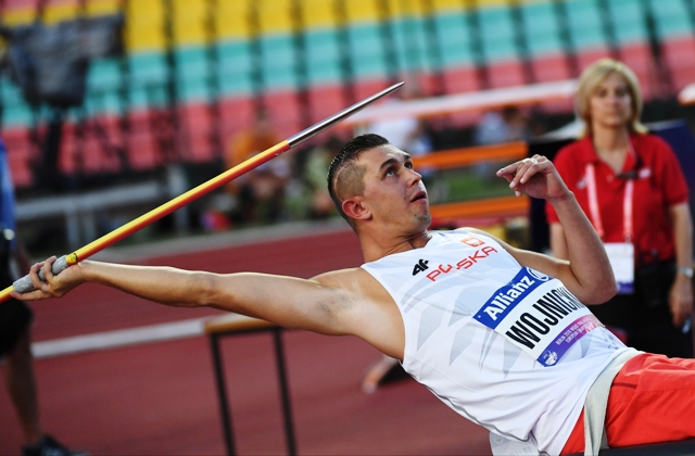 Mateusz Wojnicki wychylony do tyłu, w jednej ręce trzyma oszczep, który zaraz rzuci