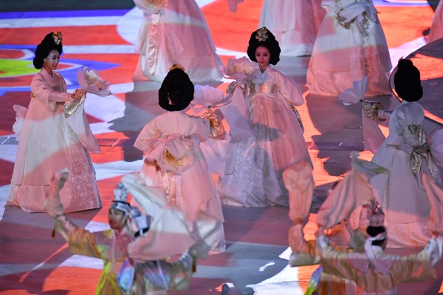 Koreanki w tradycyjnych białych suknicach i wyoko upiętych włosach wspólnie tańczą 