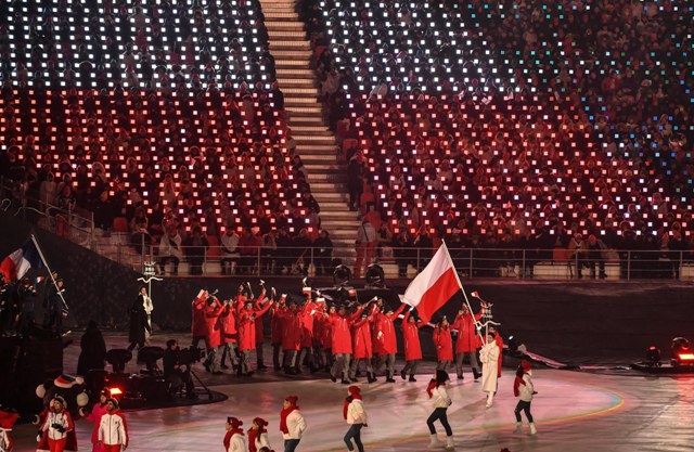 27-osobowa reprezentacja Polski. Na czele z powiewającą flagą idzie Kamil Rosiek.