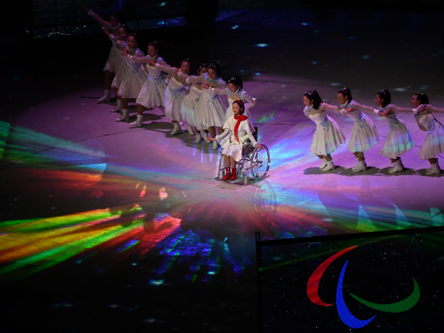 Kontynuacja tańca nastolatek - na środku sceny na wózku siedzi dziewczyna z czerwonym szalikiem - po jej obu stronach w rzędzie tańczą dziewczyny w białych sukienkach. Na scenie pad tęczowe światło