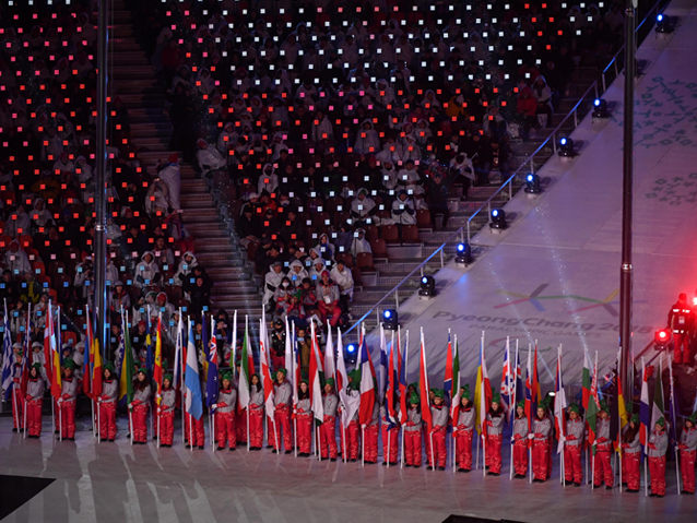 49 Koreańczyków stoją obok siebie - każdy trzyma po jeden fladze danego państwa, które brało udział w igrzyskach