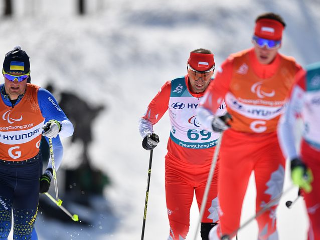 Polak biegnie na nartach za swoim przewodnikiem. Obok zawodnik z Ukrainy