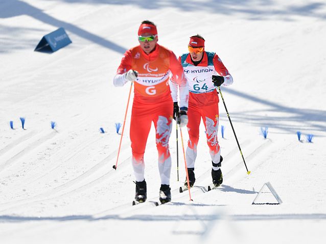 Łukasz Kubica biegnie na nartach za swoim przewodnikiem Wojciechem Suchwałko