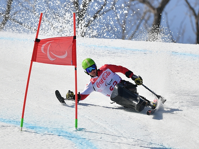Igor Sikorski mija bramkę podczas jazdy po śniegu na siedząco na jednej narcie