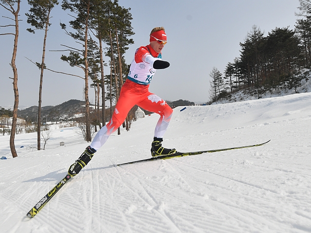 Witold Skupień, zawodnik bez rąk, podczas jazdy pod górę na nartach po śniegu