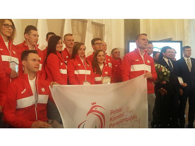 Zawodnicy, prezydent i oficjele wspólnie pozują do zdjęcia z flagą paraolimpijską