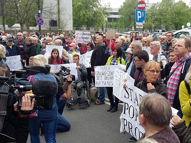 Manifestujący z transparentami stoją na ulicy