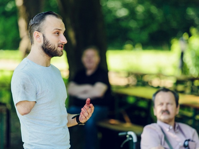 Mężczyzna bez ręki coś tłumaczy w parku