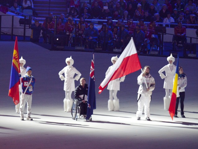 Czterech zawodników trzyma flagi ze swojego kraju, w tym Polak, na scenie głównej podczas uroczystości zakończenia Igrzysk w Soczi