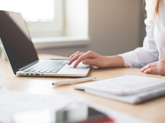 kobieta pracująca na laptopie siedzi przy stole