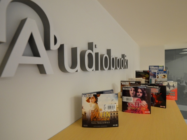 stolik na którym stoją okładki audiobooków na ścianie duży napis audiobooki