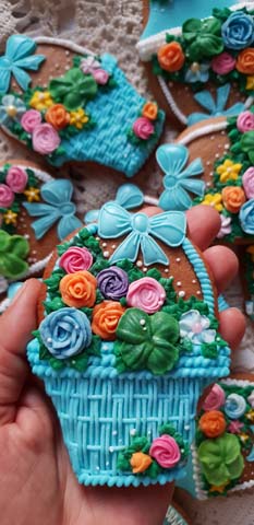 pierniki w kształcie koszyka. Są ozdobione namalowanym namalowanym ręcznie koszykiem niebieskim i kwiatkami