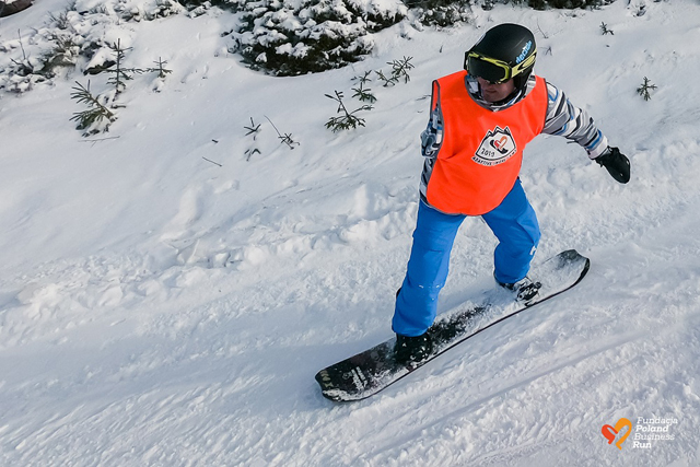 mężczyzna jedzie na snowboardzie, ma jedną rękę