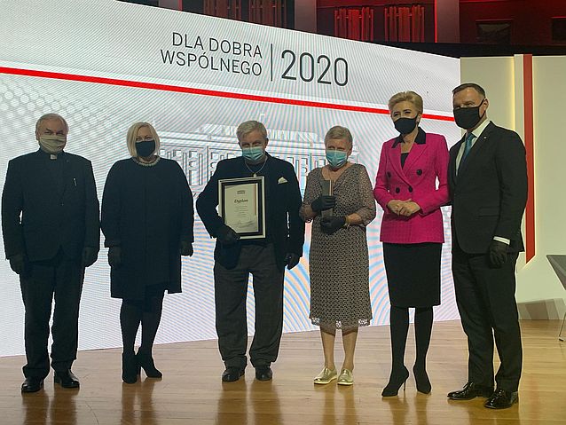 Na scenie stoi sześć osób, w tym para prezydencka, Ewa Pawłowska oraz rodzice Bartłomieja Skrzyńskiego. W tle napis: Dla Dobra Wspólnego 2020