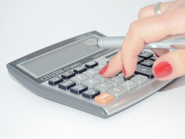 Dłoń kobiety trzymająca wieczne pióro i używająca kalkulatora