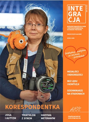 okładka magazynu Integracji nr 4/2021. Na okładce Ilona Berezowska patrzy prosto w obiektyw, ma okulary, jest ubrana w kamizelkę korespondentki z Tokio, trzyma aparat w dłoniach, ma maskotkę na ramieniu