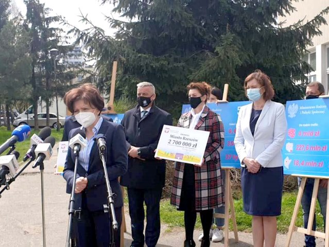 Minister Maląg przemawia przez mikrofon w czasie konferencji prasowej za nią stoją inne osoby