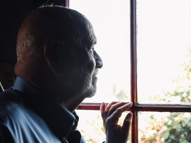 starszy mężczyzna patrzy przez okno z nostalgią