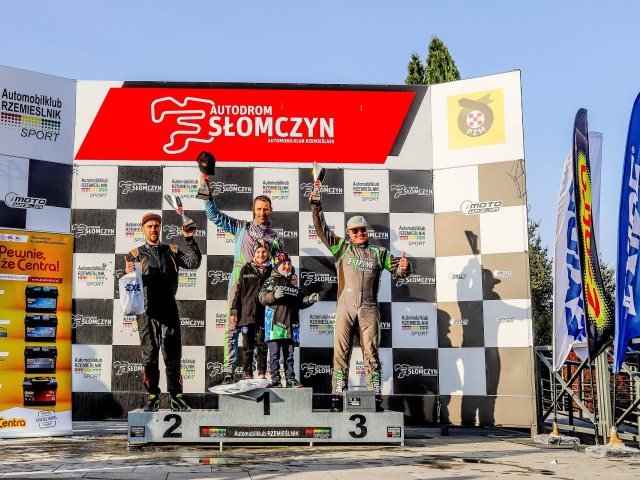 podium na tle ścianki z napisem autodrom słomczyn i zawodnicy na jego stopniach