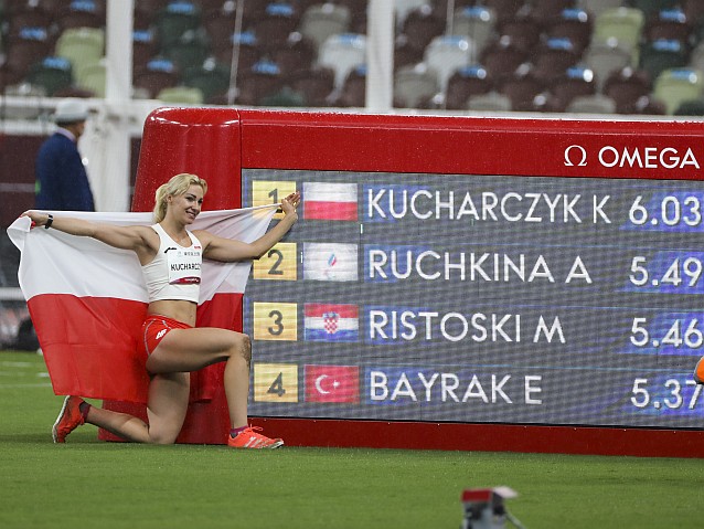 Karolina Kucharczyk pozuje z polską flagą przy tablicy wyników