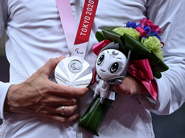 Wiszący na szyi zawodnika srebrny medal i oraz trzymany przez niego bukiet z maskotką igrzysk