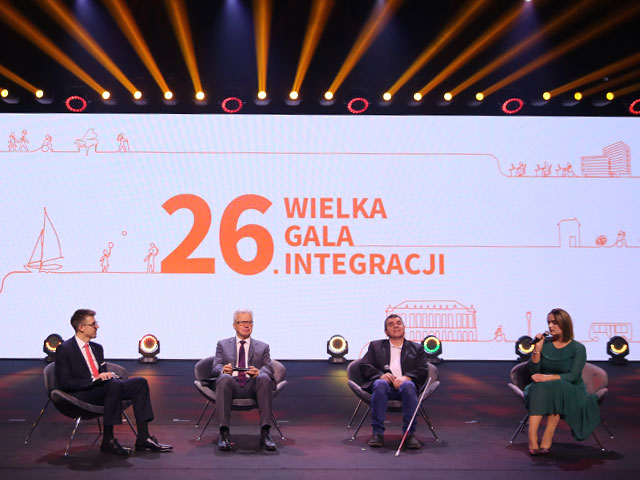 Scena Gali. W tle na telebimie napis 26. Wielka Gala Integracji. Na pierwszym planie siedzą Anna Żórawska, prezes Fundacji Kultury Bez Barier; Roman Roczeń, artysta muzyk; Krzysztof Michałkiewicz, prezes PFRON oraz prowadzący Kamil Kowalski z Integracji Lab